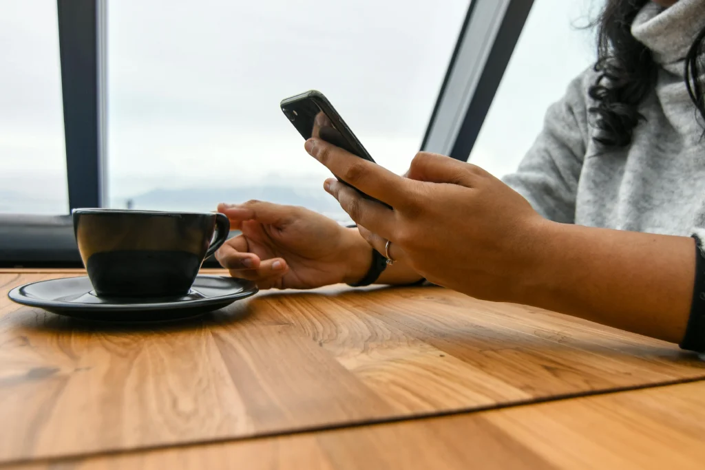 Small business owner working on phone and holding a coffee