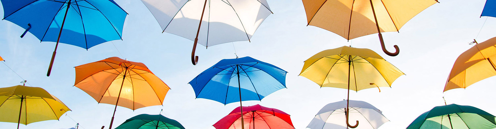 Array of rainbow umbrellas against clear blue sky