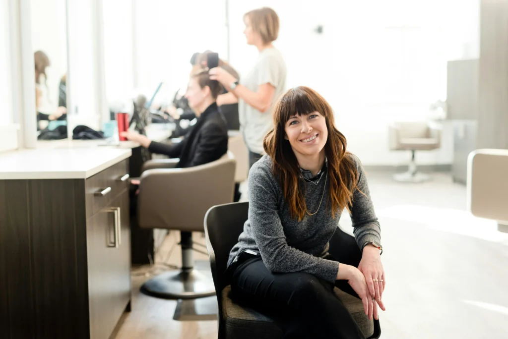 Business owner sitting in chair at hairdresser smiling to camera