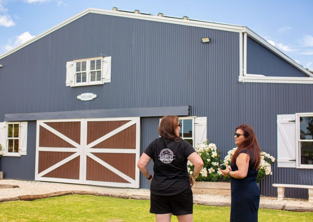 two women standing in front of a blue barn